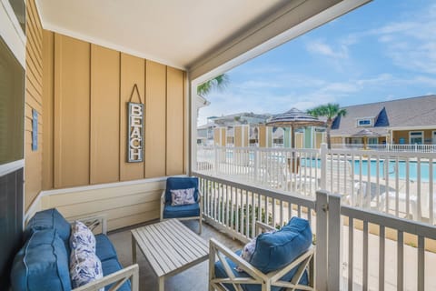 Relax on your private balcony with pool views, comfortable seating, and coastal charm—your perfect beach retreat awaits.