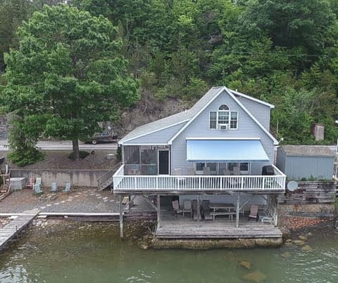 It features a large fully screened in porch, upper and lower decks with panoramic views of the lake, a relaxing 4-person hot tub available for use year-round, a private dock with a large sun deck and waterslide, and 1 vertical boat lift