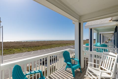 Relax on your private balcony with turquoise chairs while enjoying sweeping views of coastal marshlands and endless blue skies.