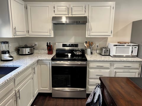 Fully equipped modern kitchen with induction range and stainless appliances.