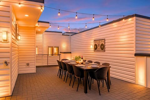 Rooftop deck dining area glowing at sunset with string lights and seating for the whole group