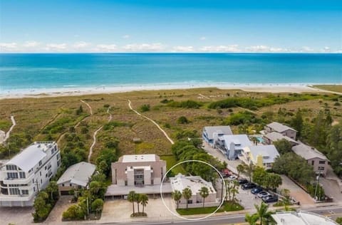 Aerial view of the Sea-Esta Mediterranean-style home with red tile roof amid tropical landscaping near Siesta Key beach and Gulf waters