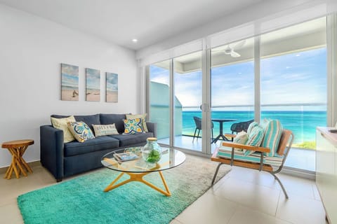 Relax in your bright living room where ocean breezes drift in and turquoise waters stretch endlessly before you, creating the perfect beachside escape.