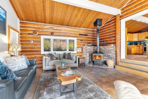 The grand living room space with vaulted ceilings, wood buring fireplace, desk, HDTV with streaming capabilities, french doors to the patio.