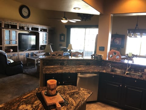 Wide view of living room, dining room, patio doors, partial kitchen.