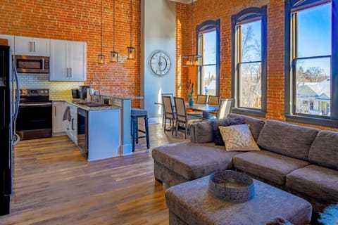 Ample natural light with large windows and an open floorplan between kitchen, living room, and dining space.