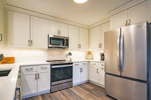 The kitchen features stainless steel appliances, a tiled backsplash, granite countertops and new cabinets.