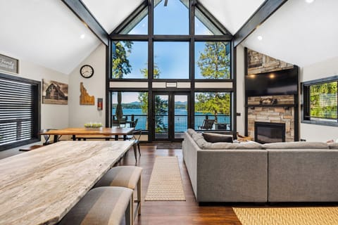 Sunlight pours through soaring windows as you sink into the plush sofa, fireplace crackling beside you. Step through those doors to your private deck overlooking the shimmering lake.