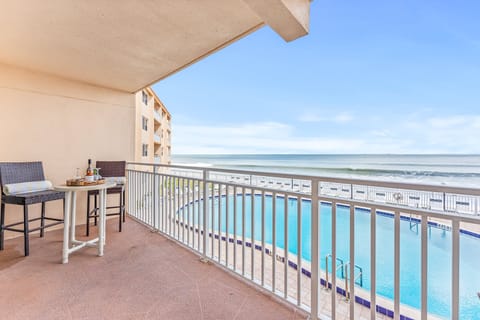 Spacious balcony with a seating area, overlooking the pool and the endless blue ocean.