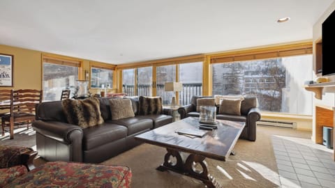 Sink into plush leather seating as sunlight pours through expansive windows framing mountain views. Your cozy retreat features rich wood accents and textured throws for ultimate relaxation.