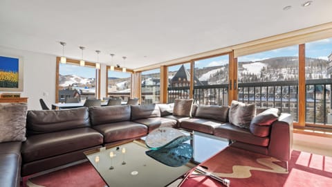 Relax on plush leather seating as natural light pours through floor-to-ceiling windows, framing breathtaking mountain views. Your perfect alpine retreat awaits with space to unwind and memories to make.