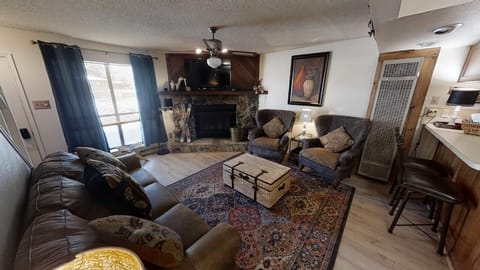 Settle into your cozy living space with plush seating and a warm stone fireplace, perfect for relaxing evenings after mountain adventures.