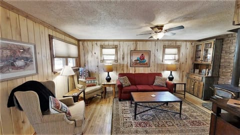 Relax in your cozy living room with rustic wood-paneled walls, plush seating, and warm lighting that invites you to unwind after a day of adventure.