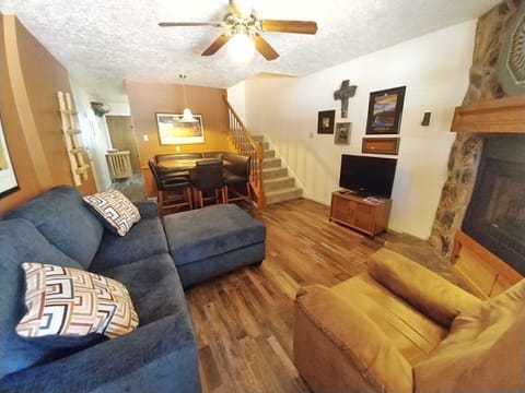 Unwind in your cozy living area with comfortable seating, warm wood accents, and a fireplace for chilly mountain evenings. The open layout connects you to the dining space and upper levels.
