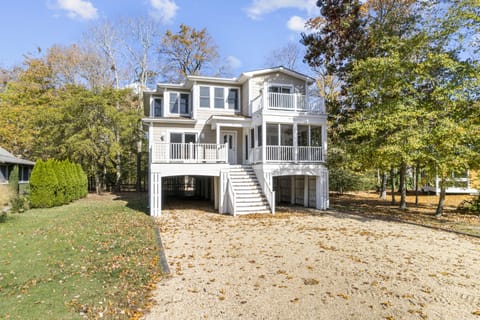 511 Doral Drive - Front Exterior - Classic multi-level coastal home featuring spacious decks, a screened-in porch, and a gravel driveway nestled among mature trees for ultimate privacy.