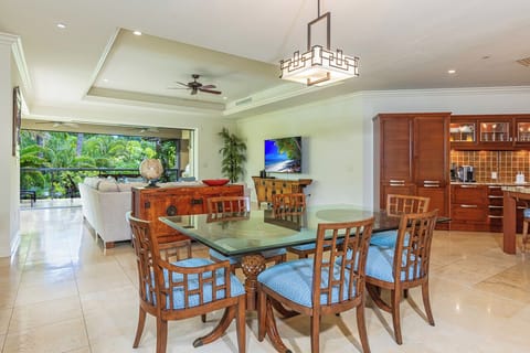 Gather with loved ones at your dining table, where a ceiling fan keeps the breeze flowing and tropical greenery awaits just beyond the open terrace doors.