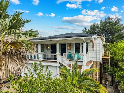 Mature palms and a covered porch welcome you to Port Side at M — a renovated retreat just an 8-minute walk from the beach.