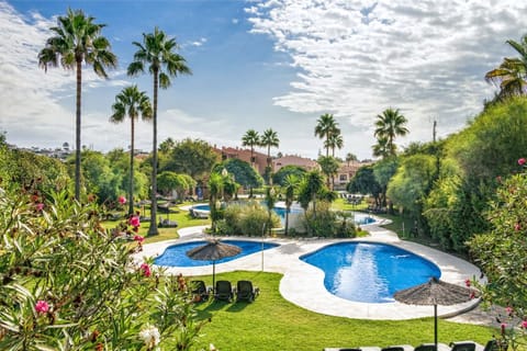 Meandering pool with island features surrounded by tropical landscaping.