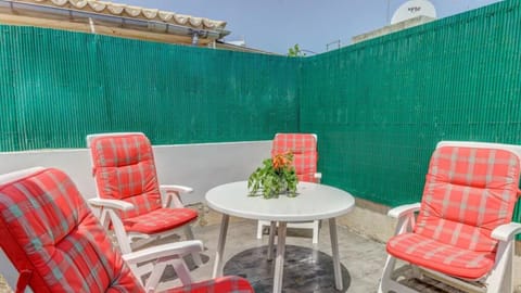 Rear patio with seating area, four padded armchairs and a round table; green privacy screen.