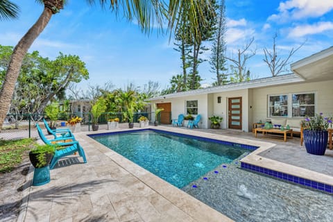 The pool boasts a baja shelf for a water immersed tanning. Patio with lounge area, chaise lounges, and additional seating areas surround the glistening pool.