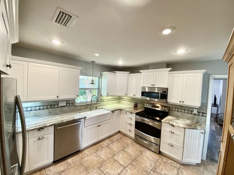 Kitchen equipped with pots, pans, utensils, plates, coffee maker, blender, etc. 