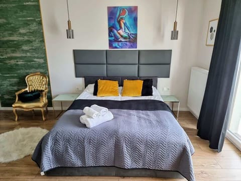 A stylish bedroom featuring a bed with a gray comforter, decorative pillows, and a colorful painting on the wall.