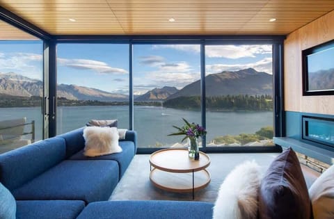 Cozy Living Room with Fireplace and Lake Views – Relax in this inviting living area with a beautiful fireplace, creating a warm, serene atmosphere. Enjoy stunning views of Lake Wakatipu and the surrounding mountains from this elegant space.