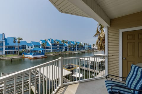Relax on your private waterfront balcony with stunning canal views, comfortable seating, and colorful houses creating a perfect coastal retreat.