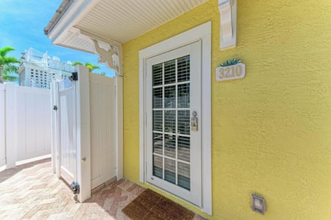 A cheerful yellow facade with decorative trim marks the entrance to this coastal vacation home, framed by swaying palms and tropical breezes.