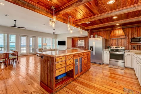 Spacious Fully Equipped Luxury Kitchen with Stainless Steel Appliances, A Large Butcher Block Island, Bar Stool Seating, and Beautiful Heart Pine Wood Walls and Beams