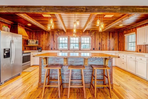 Spacious Fully Equipped Luxury Kitchen with Stainless Steel Appliances, A Large Butcher Block Island, Bar Stool Seating, and Beautiful Heart Pine Wood Walls and Beams