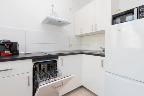 Close-up of the open dishwasher in the kitchen. A microwave oven sits on the fridge.