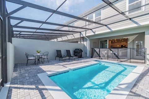 Step outside to enjoy a private pool area with a sleek screen enclosure providing sun and shade. Relax on modern outdoor furniture as you unwind by the shimmering water under the bright sky.