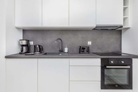 A compact kitchenette with stainless steel appliances, a sink, and modern design elements.