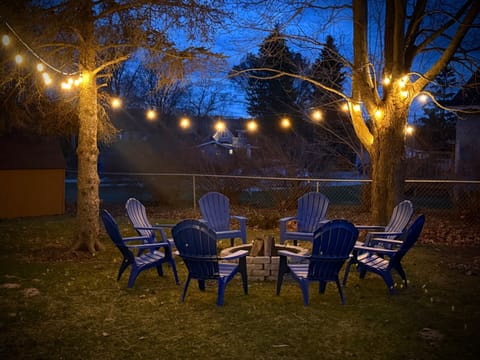 EXTERIOR:  The backyard bonfire ring lit up at night