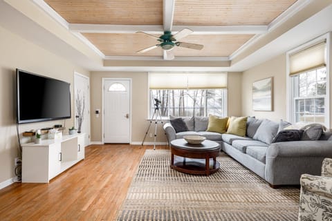 Bright living room w/ coffered wood ceiling, cozy sectional & large windows filling the space w/ natural light.