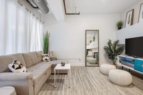 Bright living area w/ plush sofa, cozy poufs & large mirror, perfect for relaxing after a day out.