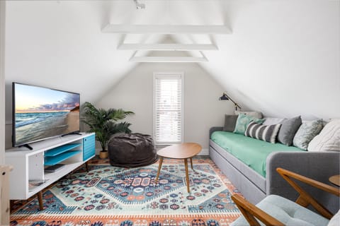 Relax in the bright living area w/ vaulted ceilings, plush sofa, colorful rug & TV for cozy movie nights.