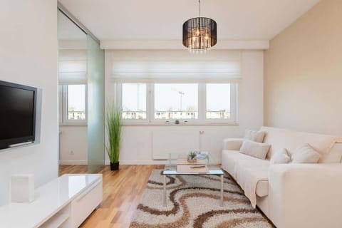  A cozy living room featuring a beige sofa, a small coffee table, and bright natural light from large windows.