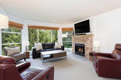 - Bright living room with mountain views and stone fireplace centerpiece  
- Plush leather seating and flat-screen TV create a cozy modern feel  
- Ideal space to unwind after skiing or hiking adventures in Whistler  