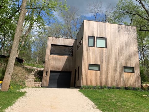 The modern new construction house is situated on a hill, with rustic wood siding