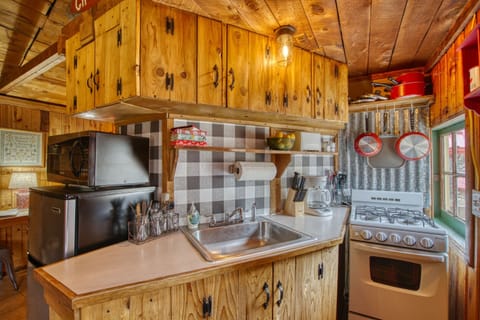 Featuring a well stocked vintage kitchenette including gas stove, microwave, minifridge & freezer, toaster, coffee maker, along with basic oils and spices, dishes and cookware.