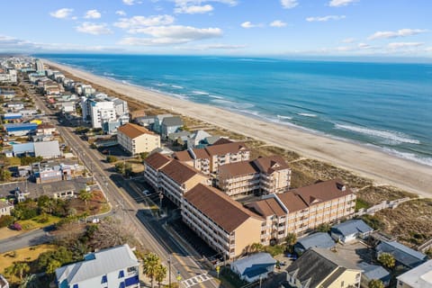 Beachfront property complex positioned directly on pristine sandy shores with expansive ocean views and coastal community surroundings.