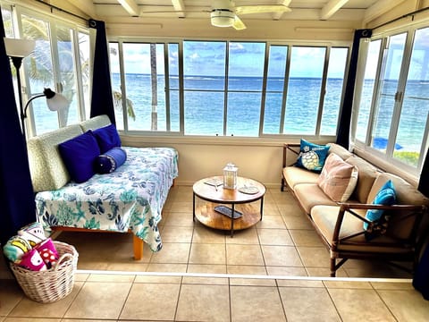 Cottage sitting area with twin bed, surrounded by ocean view on 3 sides.