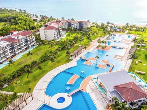Aerial view of a resort with multiple pools and lush green lawns near the beach