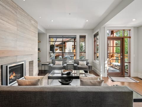 Sunken living room with indoor fireplace leading to the balcony with outdoor seating and barbecue.