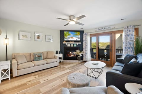 Bright living area with updated furnishings, a 55" TV, and access to the covered ocean-view deck.