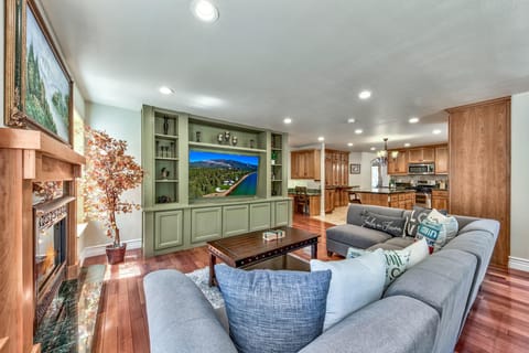 Living room with sectional sofa, wooden coffee table, green built-in media center, and a fireplace with marble hearth.