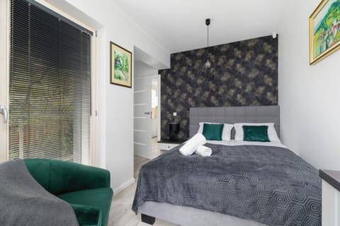 The stylish bedroom includes a comfortable double bed and an armchair.