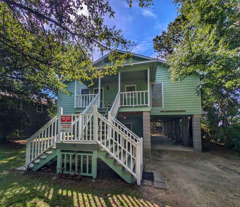 This charming coastal cottage sits nestled among mature trees in a peaceful residential setting. The property features covered front porch access, ground-level parking, and a welcoming exterior ideal for a relaxing beach getaway.
